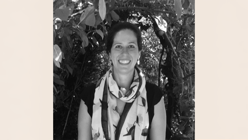 black and white photo of a smiling woman wearing a shawl with trees in the background